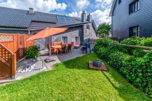 um quintal com um pátio com um guarda-chuva laranja em Ferienhaus CAMILLO em Bullange