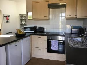 una cocina con armarios blancos y encimeras negras en Beautiful 3-Bed Cottage in Llancarfan Nr Cardiff, en Barry
