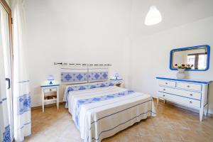 ein weißes Schlafzimmer mit einem Bett und einem Spiegel in der Unterkunft Le Case di Maiorca - PMS CaseVacanze in Budoni