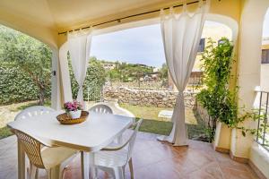 une table et des chaises blanches sur une terrasse avec une fenêtre dans l'établissement Le Case di Maiorca - PMS CaseVacanze, à Budoni