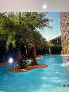 a swimming pool with palm trees in a hotel at Mai Khao Beach Apartments -MBC- in Ban Bo Sai Klang