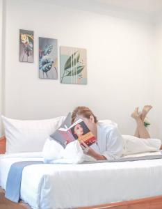 a man laying in bed reading a book at White Corner Hotel in Phnom Penh