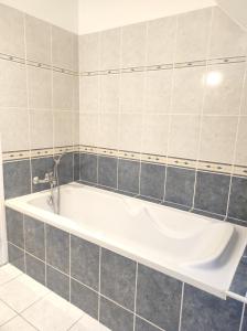 La salle de bains carrelée est pourvue d'une baignoire blanche. dans l'établissement Maison confort Trégomeur avec jardin et parking, à Trégomeur