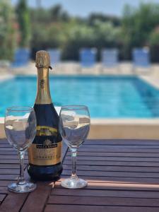 a bottle of wine and two wine glasses on a table at Villa Mari in Makris Gialos