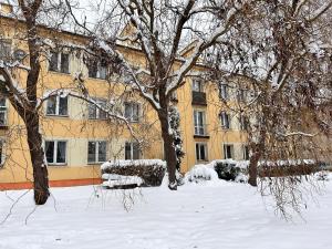 a building covered in snow with trees and bushes at Be Inn - Luxury Apartment Gliwice in Gliwice