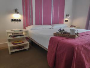 una camera con un grande letto e un tavolo con una parete rosa di Hostal Santa Ana Colors a Madrid