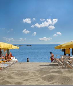 una spiaggia con ombrelloni gialli e persone sulla sabbia di Depandance Hotel Jole a Cesenatico