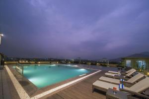 a large swimming pool with lounge chairs on a building at Distrikt 9 in Palakkad