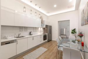 a kitchen with white cabinets and a glass table at Exclusive Csengery Residence in the heart of Budapest in Budapest