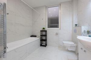 a white bathroom with a tub and a toilet and a sink at Exclusive Csengery Residence in the heart of Budapest in Budapest