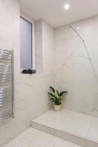 a white bathroom with a shower and a potted plant at Exclusive Csengery Residence in the heart of Budapest in Budapest
