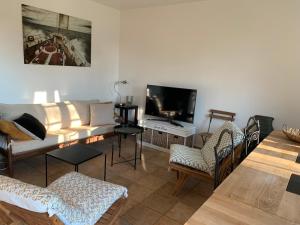 a living room with a couch and chairs and a tv at Le Bois des Pierres in Conteville