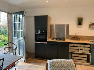 a kitchen with a stove top oven next to a table at Le Bois des Pierres in Conteville