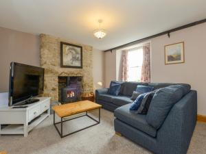 Una sala de estar con un sofá y un televisor. en Brimpts Cottage, en Postbridge