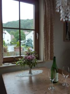 un jarrón de flores sentado en una mesa con una ventana en Ferienwohnung Haus am Singberg, en Ramsthal