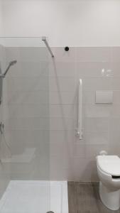 a white bathroom with a shower and a toilet at Vulcano Apartment in Catania
