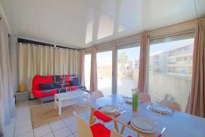 un soggiorno con tavolo e divano rosso di Appartement Terrasse vue Mer a Canet-en-Roussillon