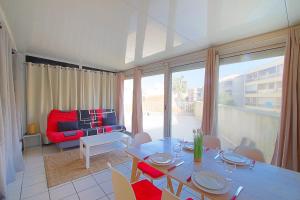 sala de estar con mesa y sofá rojo en Appartement Terrasse vue Mer, en Canet-en-Roussillon