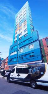 una furgoneta blanca estacionada frente a un edificio en HOTEL AMERICAN VISA CORPORATE, en Bogotá