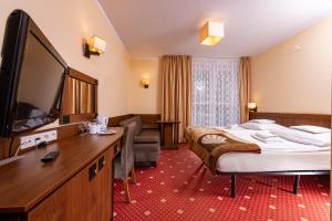 um quarto de hotel com uma cama e uma televisão de ecrã plano em Ośrodek Rekreacyjny Aga em Gąski