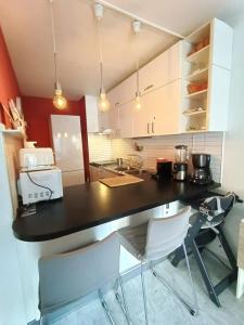 a kitchen with a black counter and white chairs at Tribuperez à Juan-Antibes in Juan-les-Pins