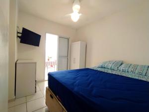 a bedroom with a blue bed and a window at Excelente Apartamento no Centro de Bertioga in Bertioga