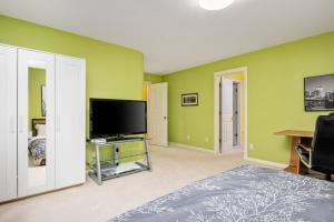 a bedroom with green walls and a flat screen tv at Seiben Creek Retreat in Clackamas