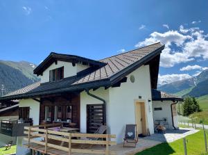 a small white house with a wooden deck at Casa Valtgeva in Sedrun