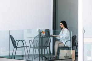 una mujer sentada en una mesa con un portátil en Akrotiri Olympus Luxury Suites - Adults Only en Plaka Litochorou