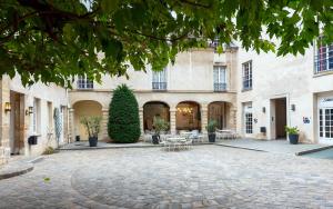 une cour d'un immeuble avec des tables et des chaises dans l'établissement MIJE MARAIS Hostel, à Paris