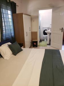1 dormitorio con 1 cama blanca grande y baño en Hgl Guest House, en East Legon