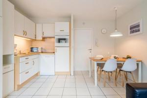 a kitchen with white cabinets and a table and chairs at Strandstudio in hartje Koksijde in Koksijde