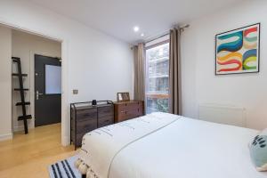 a white bedroom with a large bed and a window at D8 - Canal View Apartment in London