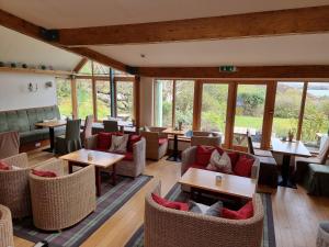 a restaurant with tables and chairs and windows at Langass Lodge in Carinish