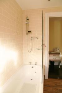 a bathroom with a tub with a shower and a sink at Number 8 The Townhouse in Derry Londonderry