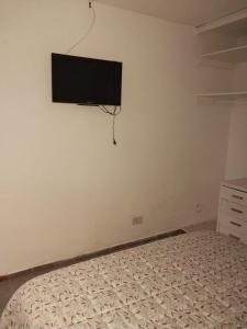 Un dormitorio con una cama y un televisor de pantalla plana en la pared. en Mendoza Alquileres D10, en Ciudad Lujan de Cuyo