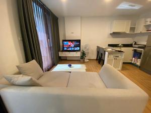 a living room with a white couch and a television at Notthing Hill Charoenkrung93 Condominium in Godown +3 photos