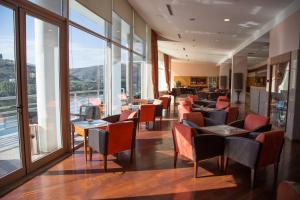 ein Restaurant mit Stühlen, Tischen und Fenstern in der Unterkunft Crisol Regua Douro in Peso da Régua