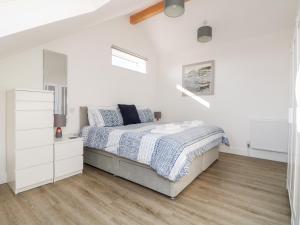 a white bedroom with a bed and a white dresser at The Crest in Helston