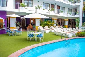 hotel z basenem, krzesłami, stołami i parasolami w obiekcie Los Arcos Suites w mieście Puerto Vallarta
