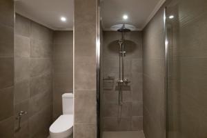 La salle de bains est pourvue de toilettes et d'une douche en verre. dans l'établissement Grammata Suites, à Ermoúpoli