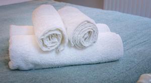 a roll of white towels sitting on a bed at Spacious Ground Floor Apartment in Keswick