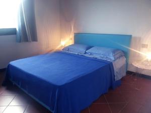 a blue bed in a bedroom with two lights on it at Villa Picasso A in Stintino