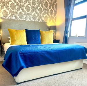 ein blaues Bett mit gelben Kissen im Schlafzimmer in der Unterkunft Killaran House in Killarney