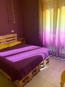 sypialnia z drewnianym łóżkiem z fioletową pościelą w obiekcie Rallegranza w mieście Napoli