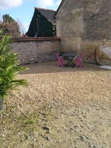 twee roze picknicktafels voor een gebouw bij La Maisonnette de Gallerie in Cour-Cheverny