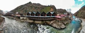 a river with buildings on the side of a mountain at Pınar Suit Bungalow in Ardeşen