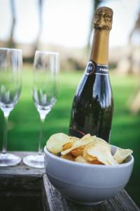 a bottle of champagne and a bowl of chips and wine glasses at Cybi at Llanfair Hall in Llanfairpwllgwyngyll