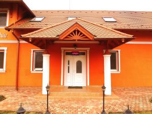 een oranje huis met een witte deur en een trap bij Horváth Vendégház in Orosháza