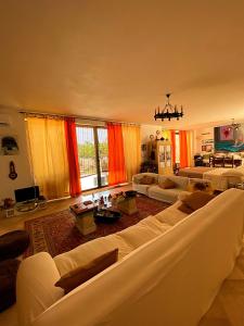 uma ampla sala de estar com mobiliário branco e cortinas cor de laranja em Palazzo Sabella Tommasi em Calimera